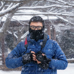 Portrait of man photographing with camera during snowfall