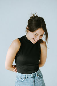 Young woman looking away while standing against white background