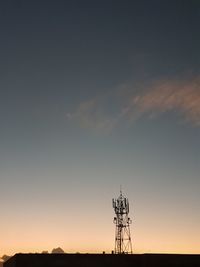 Low angle view of silhouette communications tower against sky during sunset