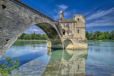 Arch bridge over river against sky