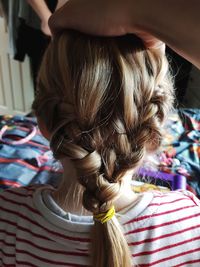 Cropped hand braiding hair of girl at home