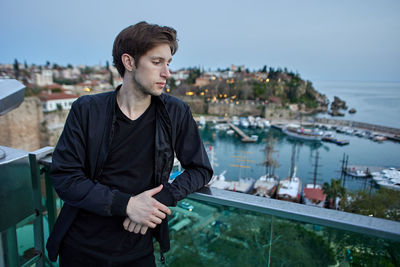 Young man looking away against sky