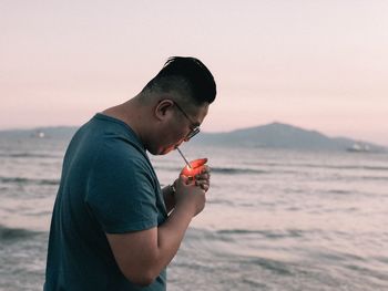 Side view of young man using mobile phone at beach