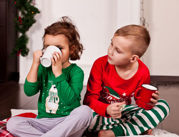 Cute girl with brother drinking hot chocolate at home