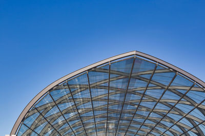 Low angle view of glass building against clear blue sky