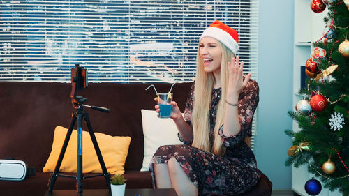 Portrait of smiling woman holding christmas tree at home