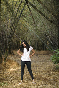 Full length portrait of young woman standing on field