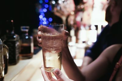 Cropped image of woman holding drink in bar