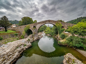 Arch bridge over river against sky