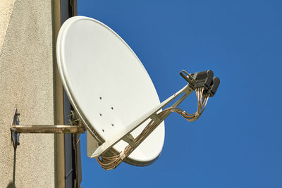 Low angle view of telephone pole against clear blue sky