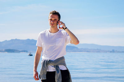 Young man walking on the beach and talking on the mobile phone