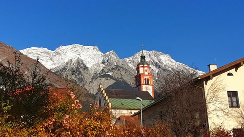 Low angle view of church and buildings against clear blue sky