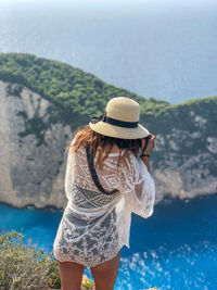 Woman wearing hat standing by sea