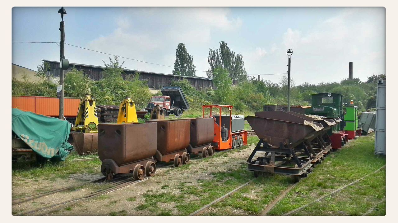 transportation, mode of transport, transfer print, land vehicle, sky, tractor, cloud - sky, grass, field, auto post production filter, men, agriculture, train - vehicle, public transportation, built structure, rural scene, cloud, farm, architecture