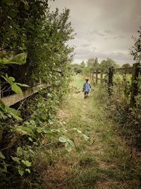 Rear view of girl walking on land against sky