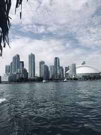 Sea by modern buildings in city against skyline and city 