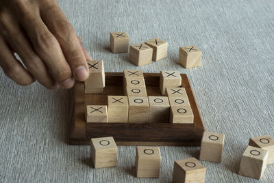 Cropped hand of person playing with toy blocks tic tac toe ox game on table