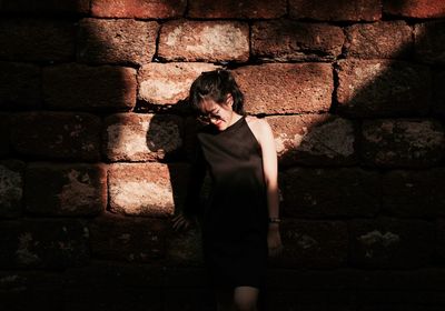 Woman standing against stone wall