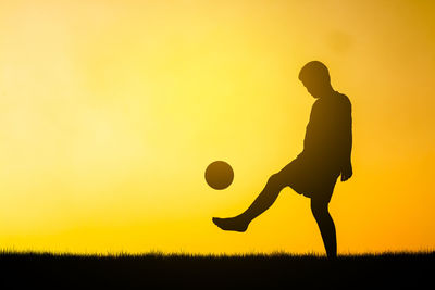 Silhouette man on field against sky during sunset