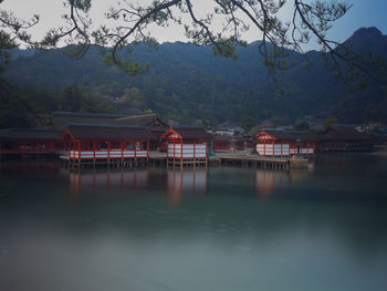 Japanese shrine by lake and mountains against sky