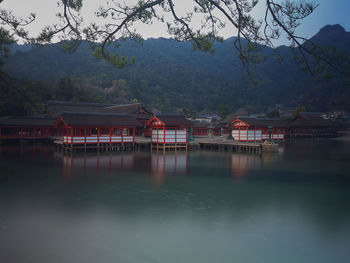 Houses by lake and mountains against sky