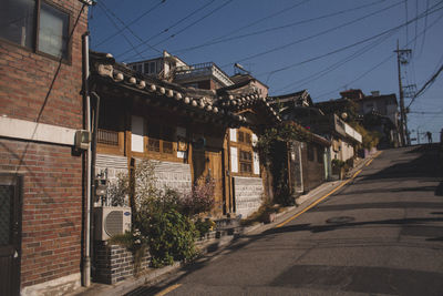Road by buildings in town against clear sky