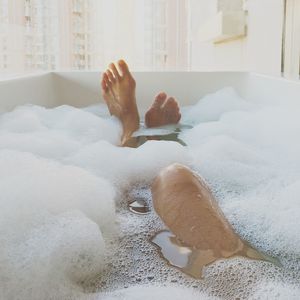 Low section of woman bathing in bathtub at home