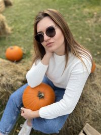 Portrait of young woman wearing sunglasses while sitting on field