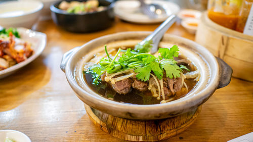 Bak kut teh, chinese pork rib soup in bowl pot on wooden table at thai restaurant in bangkok.