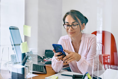 Smiling businesswoman received good news on mobile phone, sitting in office