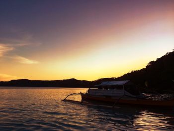 Silhouette boats moored in sea against sky during sunset