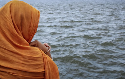Low section of woman sitting by sea