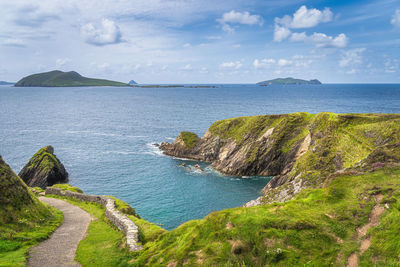 Path leading to dunquin pier surrounded by turquoise water of atlantic ocean,  ireland