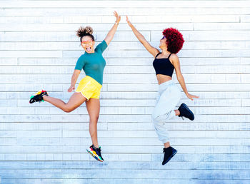 Full length of woman with arms raised while walking on wall