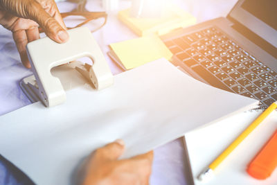 Cropped hands of businessman punching papers at desk 