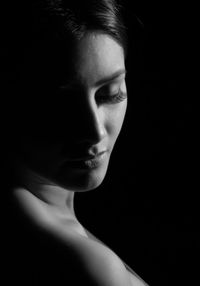 Close-up of woman looking away over black background