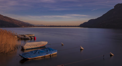 Sailboats moored on lake against sky during sunset