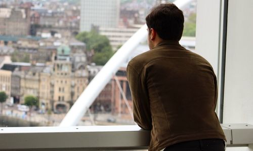 Rear view of man looking through window