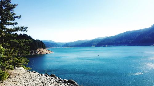 Scenic view of sea and mountains against clear blue sky