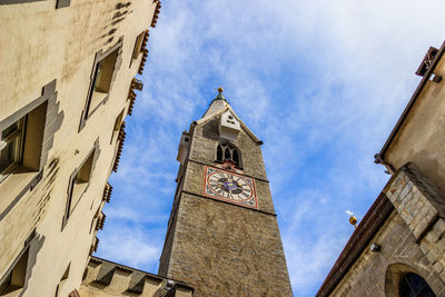 Low angle view of clock tower amidst buildings against sky