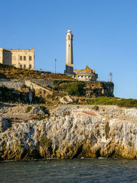 Lighthouse by sea against clear sky