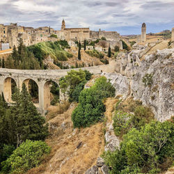 Canyon with trees, old bridge and view of buildings of an old city