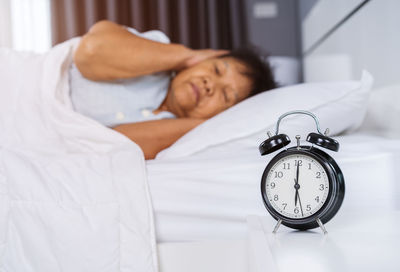 Woman sleeping with alarm clock and medicine on bed