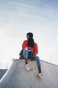 Full length of young woman looking away against sky