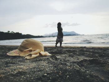 Hat with woman in background at beach against sky