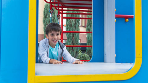 Portrait of smiling boy on slide at playground