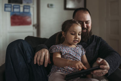 Close up of dad and young daughter playing on tablet during isolation