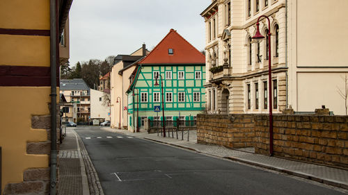 Road by buildings against sky in city