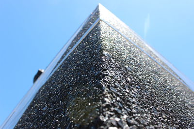 Low angle view of rough wall against blue sky