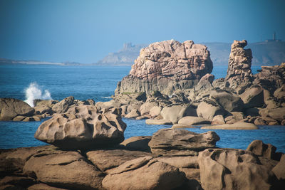 Rocks on beach against clear blue sky